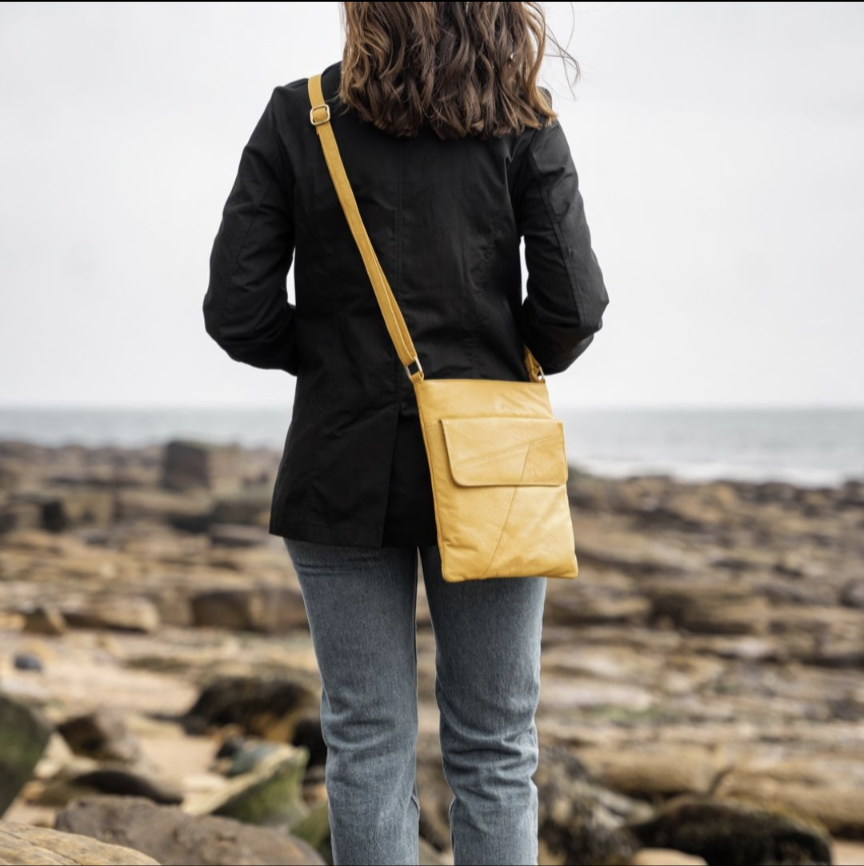 Back of lady looking out to sea wearing Mustard crossbody handbag