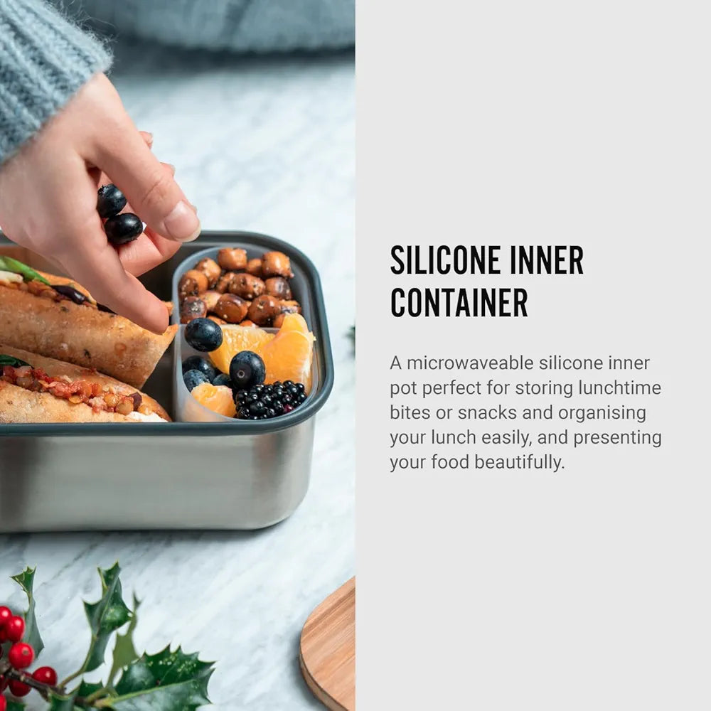 Stainless steel lunchbox with interior dish filled with nuts and fruit