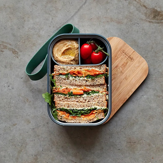 Overhead view of lunchbox with food on bamboo lid and silicone strap 