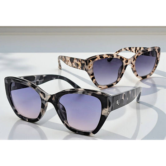 Two pairs of EyeLevel Grace ladies fashion sunglasses displayed on a white surface, featuring bold square frames with gradient lenses—one in black marble and one in tortoiseshell, styled in natural light