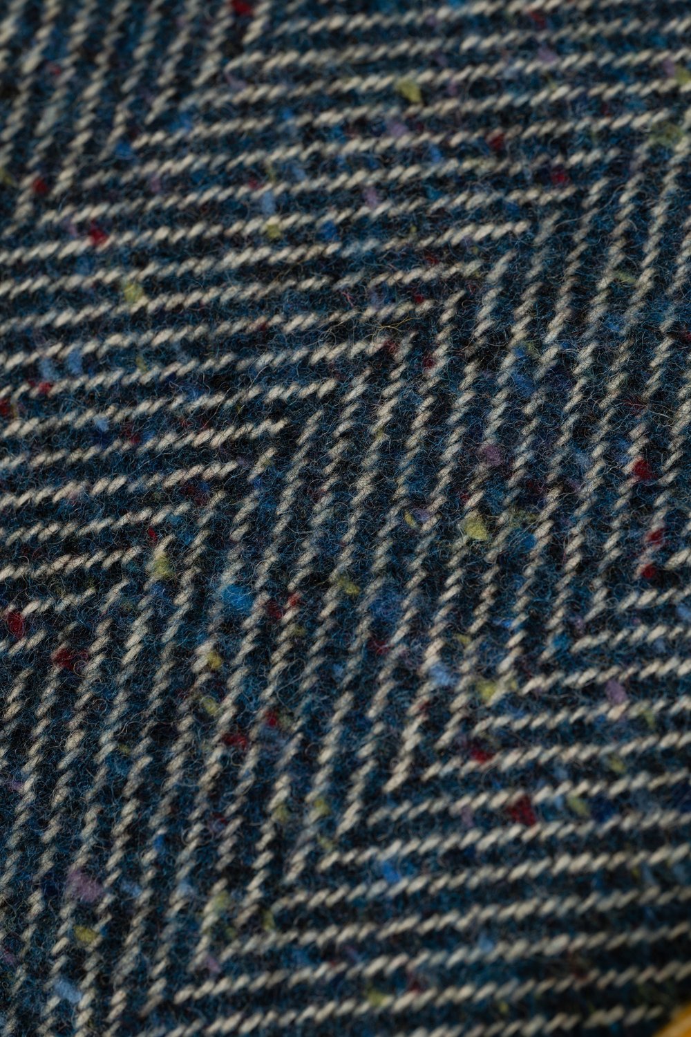 Close-up of McNutt Arranmore Donegal tweed showing blue herringbone weave and distinctive multicoloured flecks