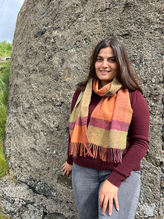 A woman wearing McNutt FOREVER Harvest recycled Merino wool scarf in red, orange and green check.