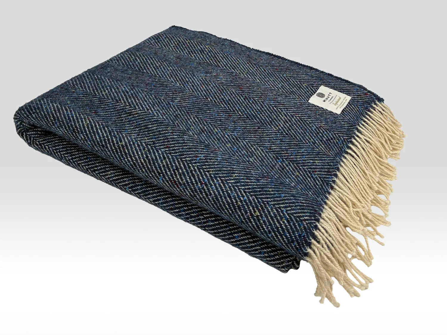 McNutt Arranmore Donegal tweed throw folded, showing Atlantic-blue herringbone pattern and cream fringe