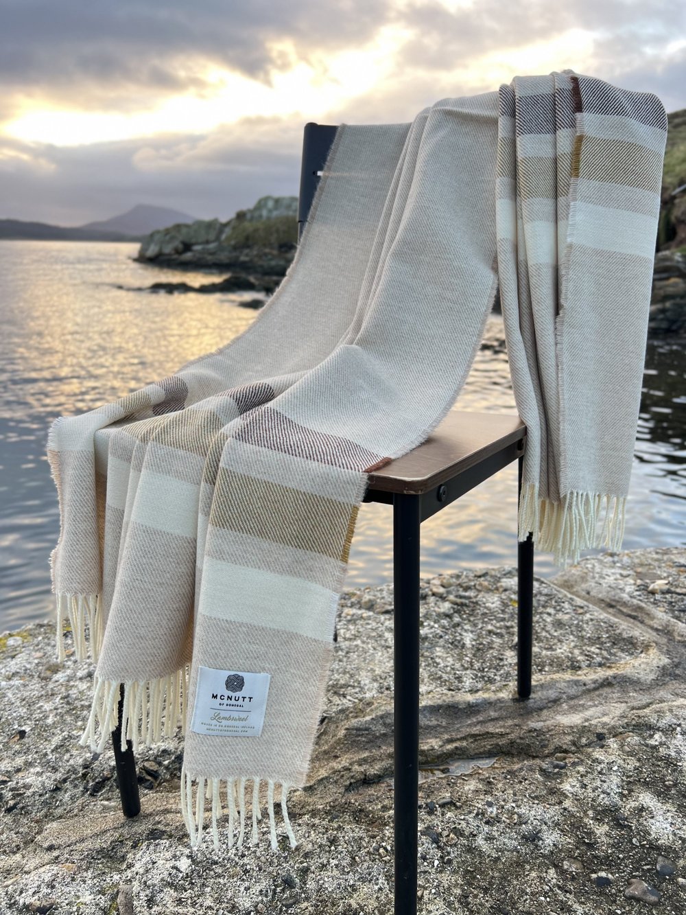 McNutt Toffee Roast Merino lambswool throw displayed outdoors, showing its full neutral woven design